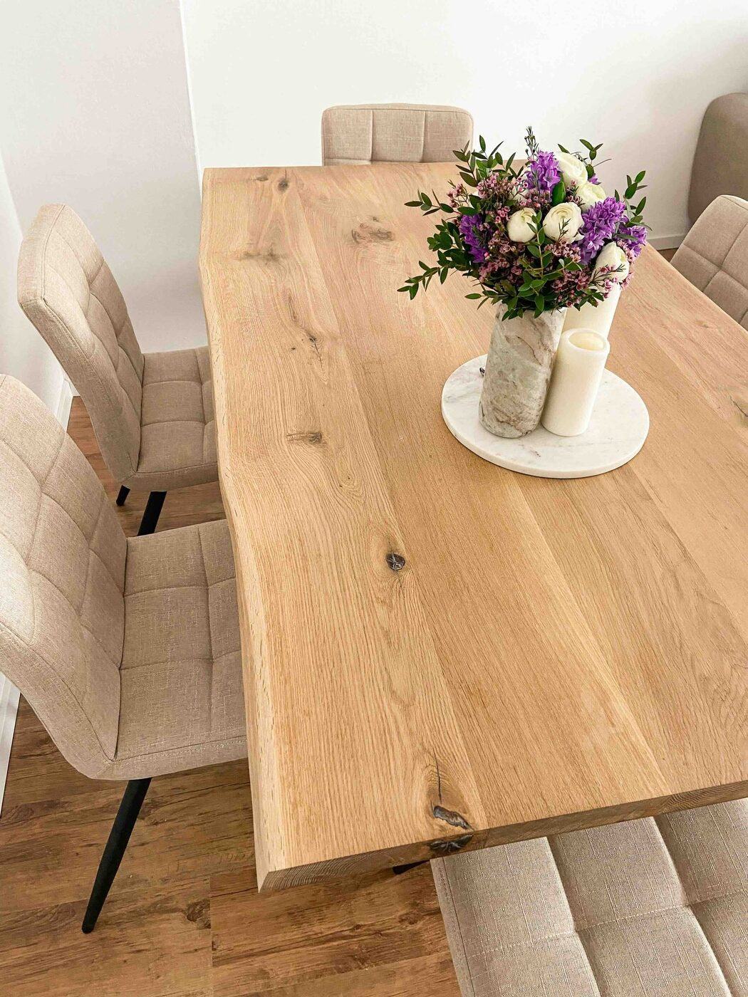 Eichentisch mit Blumenvase und beigen Polsterstühlen